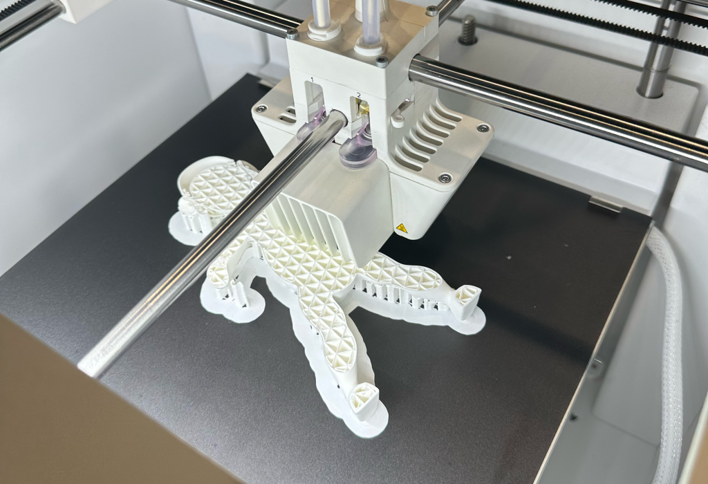 3D-mallinnuksessa oleva hahmo, etualalla on 3D-tulostin.