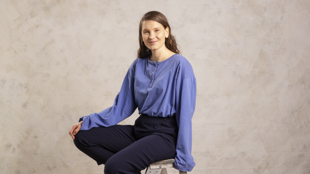 Laura Rantanen sitting on a chair and smiling at the camera.